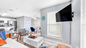 Un salon moderne avec un canapé blanc, une table basse et un téléviseur fixé au mur.