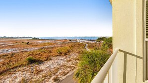 Une vue sur la côte depuis un balcon, avec une plage de sable et une végétation clairsemée.