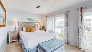 Ein Schlafzimmer mit einem großen Bett, einem Nachttisch, einer Bank und einem Fenster mit Vorhängen.