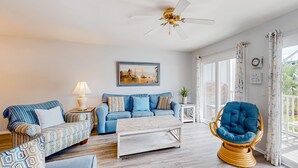 Ein Wohnzimmer mit einem blauen Sofa, einem gemusterten Sessel und einem Holztisch.