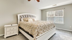 A bedroom with a bed, nightstand, ceiling fan, and window with blinds. - Community Pool! East ATL Base Near Mercedes-benz (Atlanta)