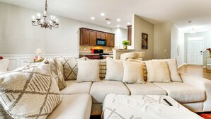 A modern living room with a sectional sofa, a chandelier, and a kitchen in the background. - Community Pool! East ATL Base Near Mercedes-benz (Atlanta)
