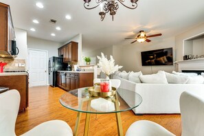 A modern living room with a glass coffee table, white sofa, and wooden flooring. - Community Pool! East ATL Base Near Mercedes-benz (Atlanta)
