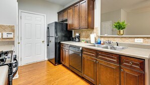 A kitchen with wooden cabinets, a stainless steel sink, and a refrigerator. - Community Pool! East ATL Base Near Mercedes-benz (Atlanta)