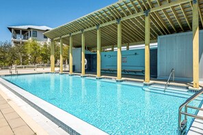 A swimming pool with a covered area and a building in the background. - Coastal home with 2 community pools, bikes, front porch & balcony - near beach (Santa Rosa Beach)