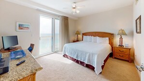 Habitación de hotel con cama, escritorio con ordenador, televisión, balcón y ventilador de techo.