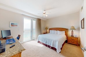 A hotel room with a bed, a desk with a computer, a TV, a balcony, and a ceiling fan. - Gulf-front 21st-floor condo with hot tub, pool, tennis, gym, balcony, beach view (Panama City Beach)