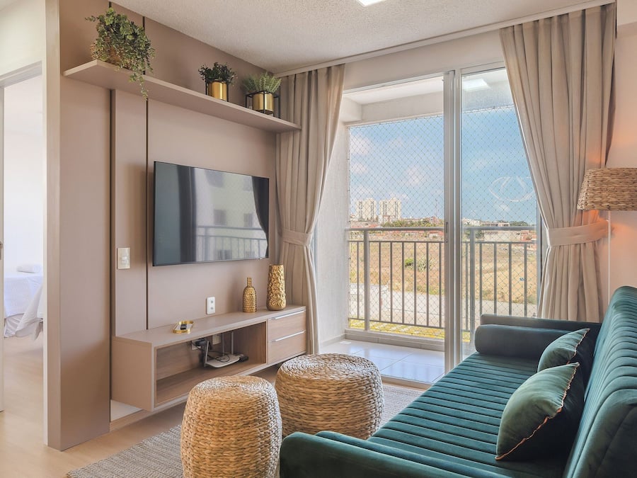A modern living room with a sofa, TV, and plants on shelves.