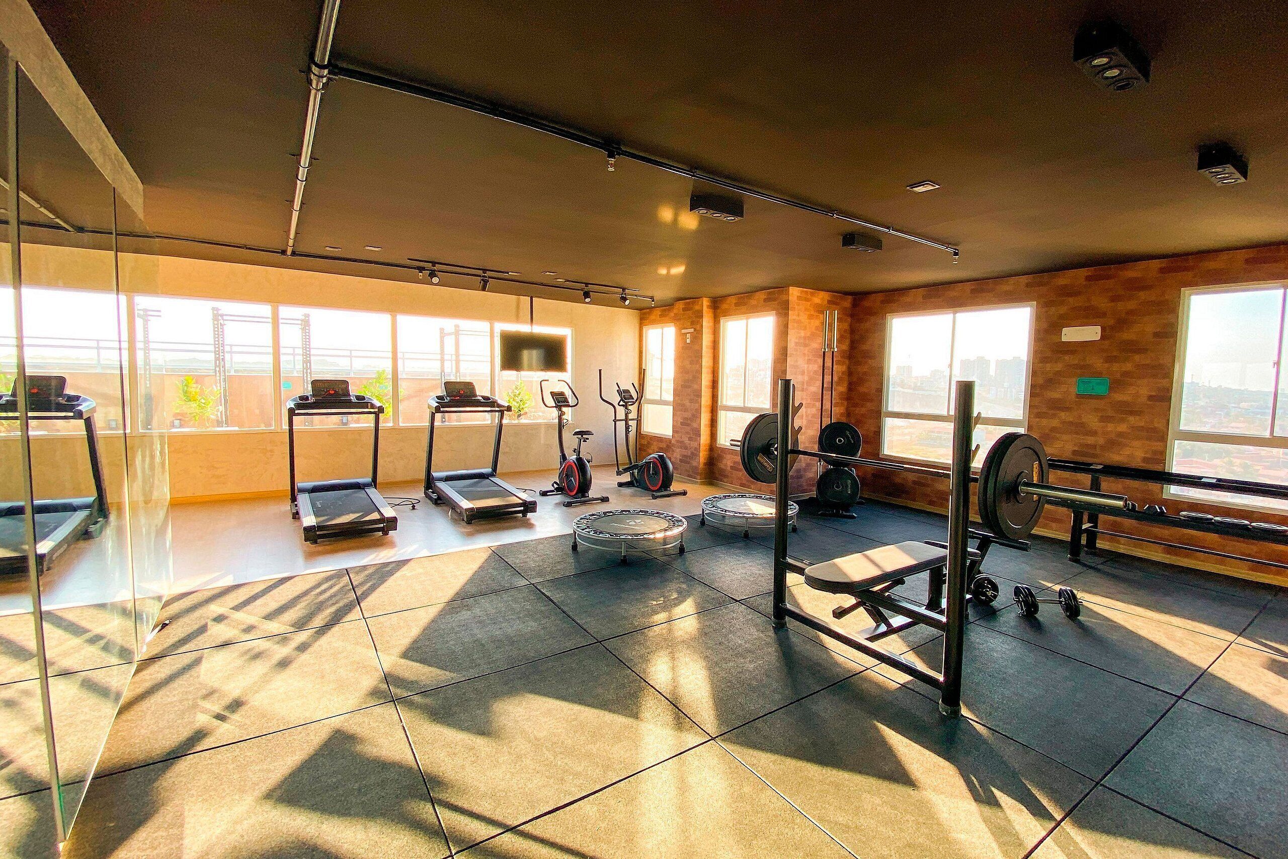 A gym with exercise equipment, large windows, and a view of the city.