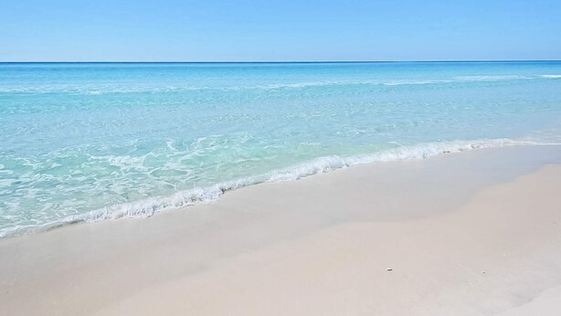 Ein Strand mit klarem türkisblauem Wasser und einem sandigen Ufer.