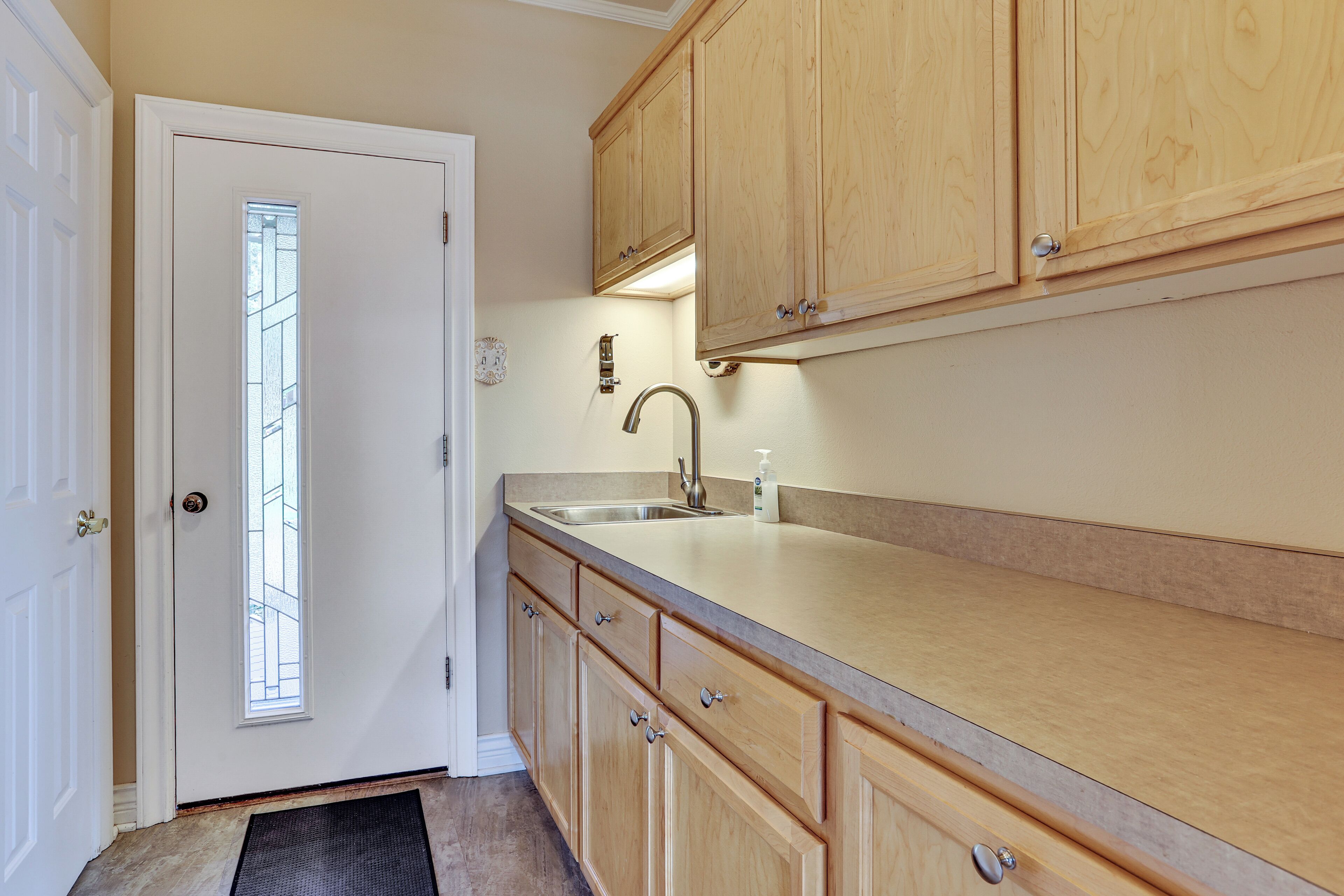 A kitchen with wooden cabinets, a stainless steel sink, and a window with a view.