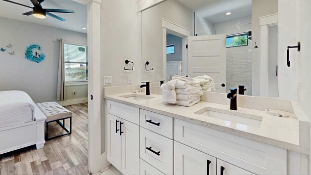 A modern bathroom with a large mirror, two sinks, and a ceiling fan. - Gorgeous coastal home, dog friendly, private hot tub & close to beach (Panama City Beach)