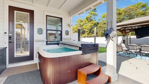 A hot tub with a wooden exterior, a door with a window, and a covered patio area with outdoor furniture. - Gorgeous coastal home, dog friendly, private hot tub & close to beach (Panama City Beach)