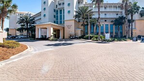 A hotel with a central entrance, palm trees, and a paved driveway. - Upscale condo with pools, private beach access, hot tubs & tennis - dog-friendly (Panama City Beach)