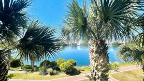 A view of a lake surrounded by palm trees and a brick pathway. - Upscale condo with pools, private beach access, hot tubs & tennis - dog-friendly (Panama City Beach)