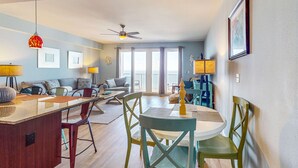 A modern living room with a dining area, a ceiling fan, and large windows. - Gulf View & Laketown Wharf Condo with full kitchen, shared pool and beach access (Panama City Beach)