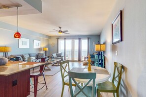 Ein modernes Wohnzimmer mit Essbereich, Deckenventilator und großen Fenstern.