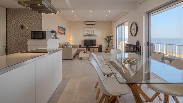 Um apartamento moderno com cozinha, sala de estar e varanda com vista para o mar.