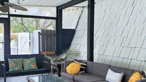 Ein moderner Außenbereich zum Verweilen mit Glastisch, gepolsterten Sofas und dekorativen Kissen.