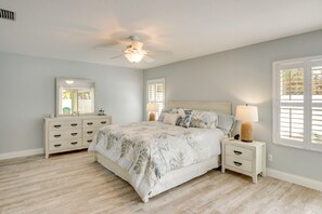 A bedroom with a bed, nightstands, a dresser, a ceiling fan, and a window with shutters. - Stroll to Shore: Pet-friendly Flagler Beach Escape (Flagler Beach)