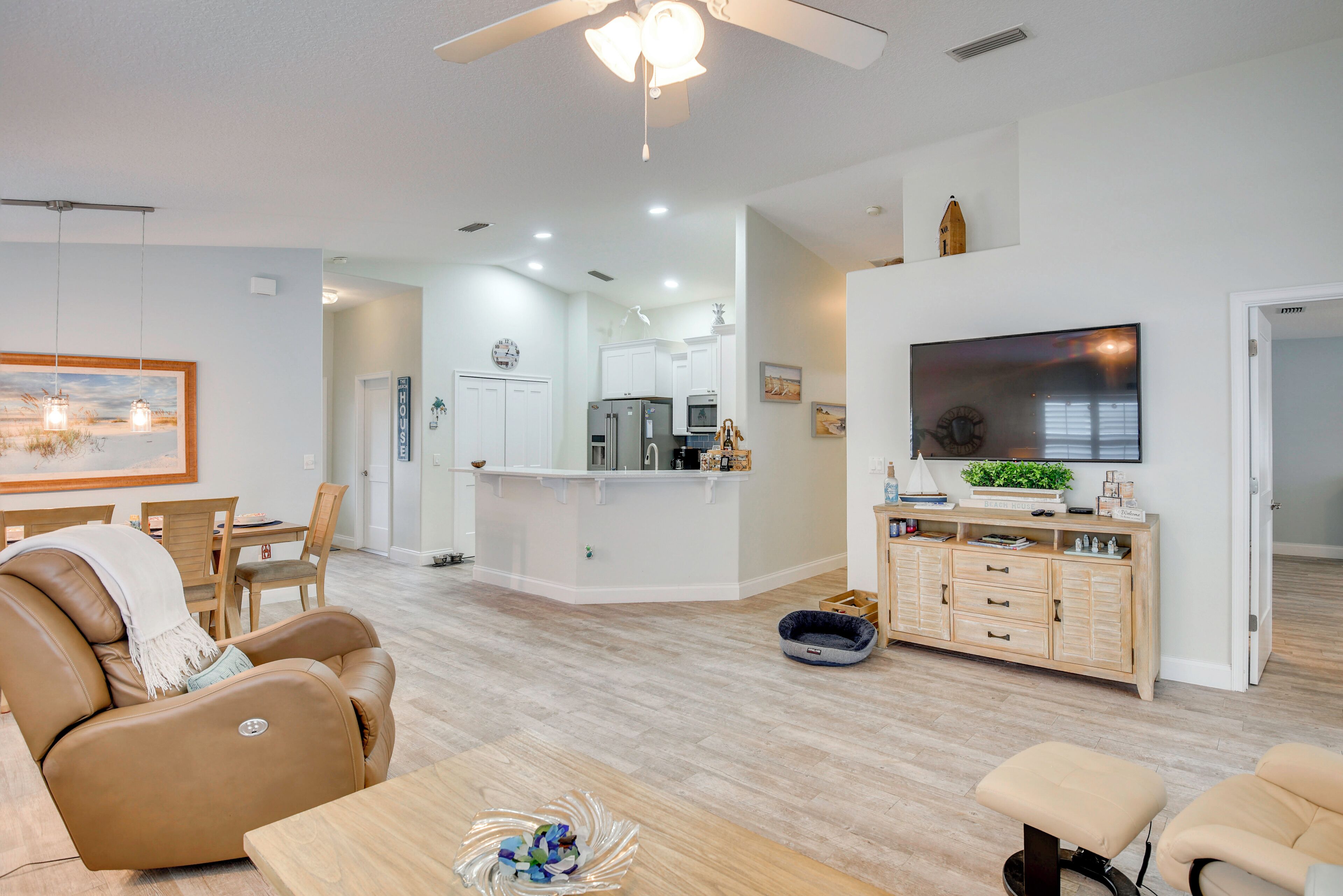 A modern living room with a leather recliner, a wooden coffee table, and a TV on a wooden cabinet.