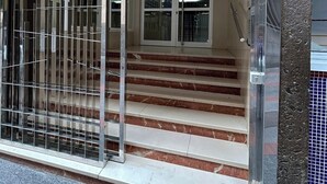 A building entrance with a metal gate, a staircase leading to an interior, and a tiled floor. - Miguel Rosas (Las Palmas de Gran Canaria)