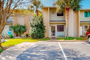 A two-story building with numbered doors, a parking lot, and surrounding greenery. - Gulf Highlands condo with pool, hot tub, tennis, fitness center, & private patio (Panama City Beach)