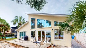 A modern house with a patio, outdoor seating, and a pool. - Lagoon-front home with dock & soaking bathtub (Panama City Beach)