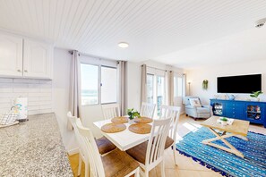 Ein modernes Wohnzimmer mit Essbereich, weißen Möbeln und einem großen Fenster, das für natürliches Licht sorgt.