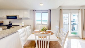 Una cocina moderna con armarios blancos, microondas integrado y encimera de granito.