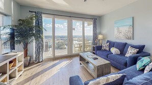 Un salon spacieux avec un balcon, un ventilateur de plafond et une grande plante.