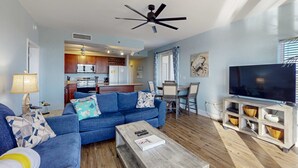 Un salon comprenant un canapé, une table basse, un meuble pour la télévision et un ventilateur de plafond.