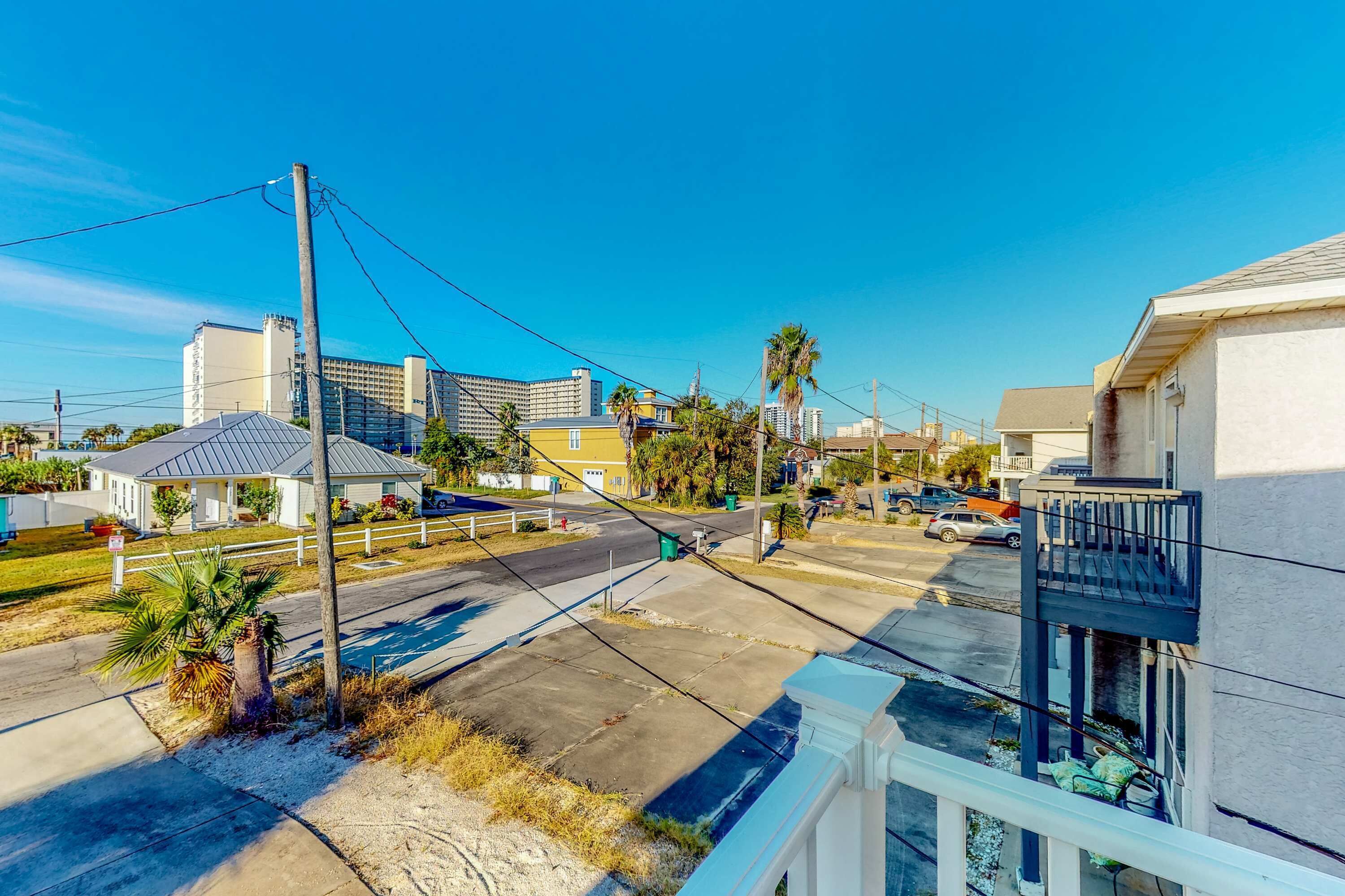 Zona residencial con calle, casas y un edificio alto al fondo.