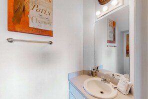 A bathroom with a sink, mirror, and towel rack. There is a sign on the wall and a towel hanging on the rack. - Lovely coastal home close to the beach and everything (Panama City Beach)
