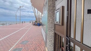 A coastal walkway with a stone wall, a metal railing, and a clear view of the sea. - Estudio en primera línea de playa (Las Palmas de Gran Canaria)