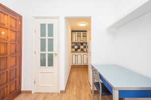 A compact room with a wooden door, a small kitchenette, and a table. - Estudio en primera línea de playa (Las Palmas de Gran Canaria)