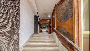 A staircase with stone wall on one side and wooden paneling on the other, leading to a door at the top. - Estudio en primera línea de playa (Las Palmas de Gran Canaria)