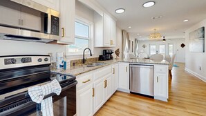 A modern kitchen with white cabinets, stainless steel appliances, a granite countertop, and a dishwasher. - Nautical home in beach community with Water views close to beach access (Navarre)