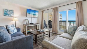 Un salon comprenant un canapé, une table basse, une lampe, un téléviseur et un balcon avec vue.