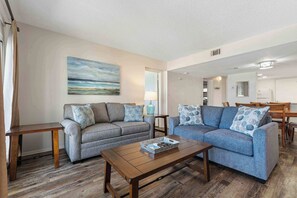 Ein Wohnzimmer mit zwei Sofas, einem Couchtisch und einem Gemälde an der Wand.
