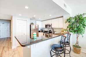 A modern kitchen with white cabinets, stainless steel appliances, and a central island with bar stools. - Beachfront condo on 10th floor w/shared pools (4), hot tub, tennis - great views (Panama City Beach)