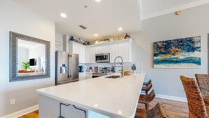 Une cuisine moderne avec des armoires blanches, des appareils en acier inoxydable et un grand îlot central.