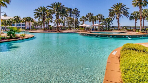 Une piscine d’un bleu éclatant, entourée de palmiers et de chaises longues.