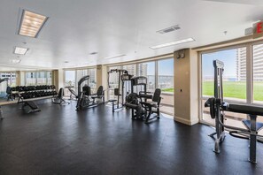 Ein Fitnessstudio mit unterschiedlichen Trainingsgeräten, großen Fenstern und Blick auf ein Gebäude.