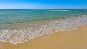 Ein Strand mit klarem, blauem Wasser und sandigem Ufer.