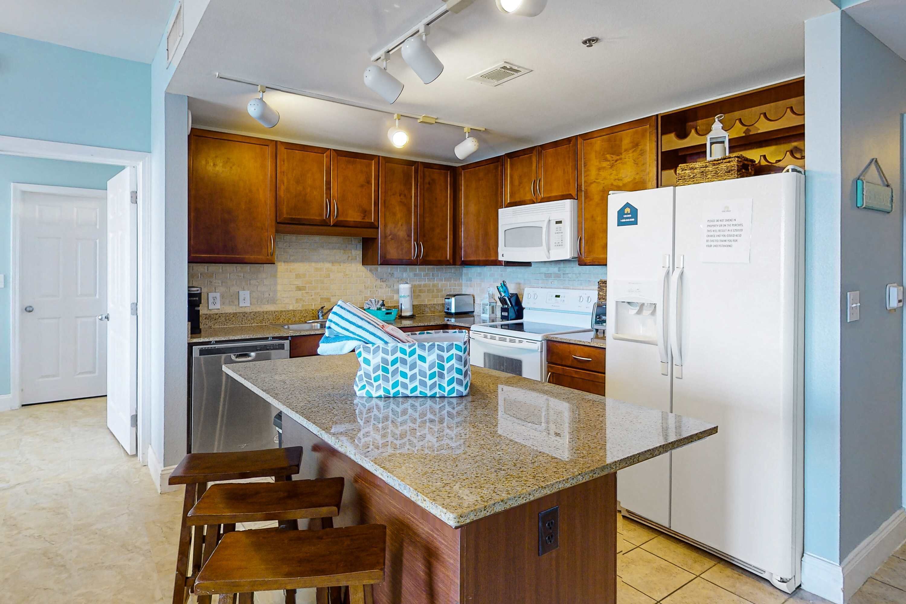 A kitchen with wooden cabinets, a white refrigerator, a microwave, and a granite countertop.