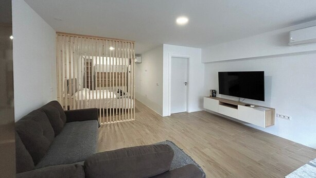 A modern living room with a sofa, a TV, and a wooden partition. - Las Tabaibas beach house (San Bartolomé de Tirajana)