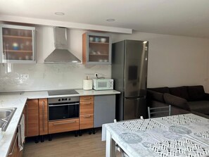 Eine moderne Küche mit einem Edelstahl-Kühlschrank, einem Einbauofen und einer Mikrowelle auf der Arbeitsfläche.