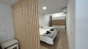 A modern bedroom with two beds, a wooden partition, and a small desk. - Las Tabaibas beach house (San Bartolomé de Tirajana)