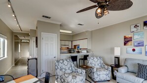 Een woonkamer met een bank, twee fauteuils, een eettafel en een plafondventilator.